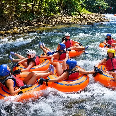 Grupo descendo o rio em boias com capacete e colete salva-vidas