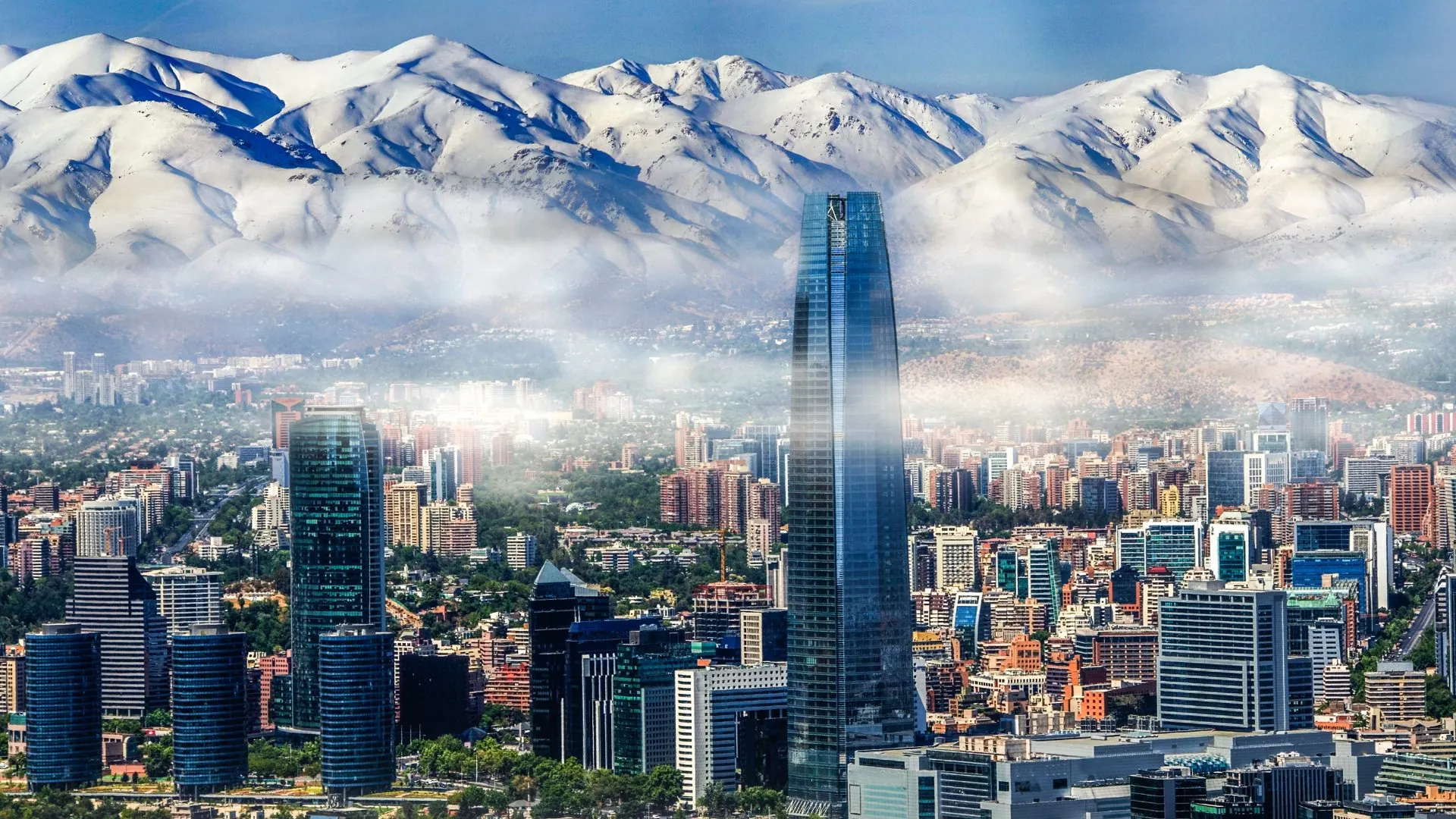 Prédios de Santiago, com a Gran Torre Costanera em destaque, diante da Cordilheira dos Andes coberta de neve