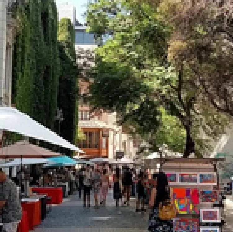 Rua arborizada do bairro Lastarria com barracas de artesanato e pedestres